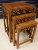 A nest of three Chinese hardwood occasional tables with fretwork carved frieze raised on moulded