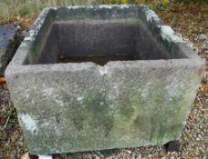 A large natural stone rectangular trough raised on four block bases,