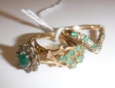 Three various 9 carat gold and emerald dress rings, one of flower head design,