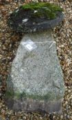 A natural stone staddle stone with circular top on a tapered base,