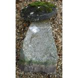 A natural stone staddle stone with circular top on a tapered base,