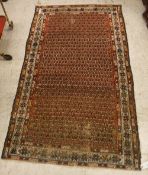 A Malayer rug, the central panel set with all-over stylised hook motifs on a red ground,