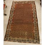 A Malayer rug, the central panel set with all-over stylised hook motifs on a red ground,