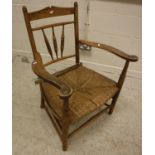 A Provincial stained beech framed spindle back rush seat elbow chair on turned legs 63 cm wide x 84