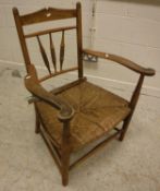 A Provincial stained beech framed spindle back rush seat elbow chair on turned legs 63 cm wide x 84