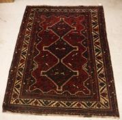 A Persian rug with three repeating lozenge medallions on a red ground, within a cream ground border,