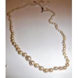 A pearl single strand necklace with white metal diamond encrusted barrel shaped clasp,