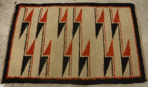 A modern Navaho rug, the central panel set with geometric orange and black design on a cream ground,
