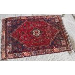 A Persian rug with centre lozenge medallion on a red ground,