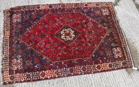 A Persian rug with centre lozenge medallion on a red ground,