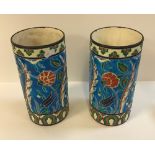 A pair of Longwy vases of cylindrical form with floral decoration on a turquoise ground,
