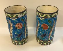 A pair of Longwy vases of cylindrical form with floral decoration on a turquoise ground,