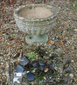 A Haddonstone type garden urn of reeded form in the 19th Century manner, raised on a circular foot,
