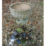 A Haddonstone type garden urn of reeded form in the 19th Century manner, raised on a circular foot,