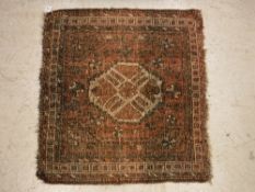 A Caucasian rug, the central panel set with lozenge shaped medallion on a salmon pink ground,