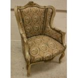 A painted and gilt framed wingback chair in the Louis XV taste raised on cabriole legs to scroll
