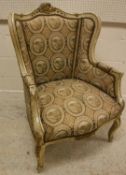 A painted and gilt framed wingback chair in the Louis XV taste raised on cabriole legs to scroll