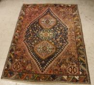 A Persian rug, the central panel with repeating medallions on a blue ground,