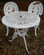 A white painted metal garden table and two chair in the Victorian style