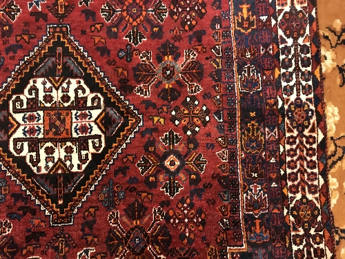 A Persian rug with centre lozenge medallion on a red ground, - Image 8 of 17
