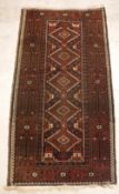 A Belouch rug, the central panel set with repeating diamond medallions on a dark ground,
