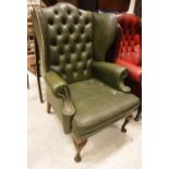 A buttoned green leatherette upholstered wing back scroll arm chair in the Georgian manner,