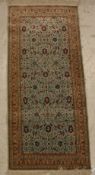 A Qum silk rug, the central panel set with all-over floral decoration on an aquamarine ground,