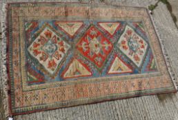 A Turkish carpet, the central panel set with three repeating medallions on a blue ground,