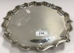 A George V pie-crust silver salver, raised on three hoof feet (by Elkington & Co.