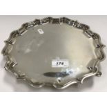 A George V pie-crust silver salver, raised on three hoof feet (by Elkington & Co.