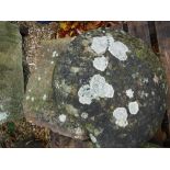 A natural stone staddle stone with circular top on a tapered base,