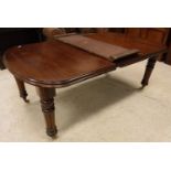 A Victorian mahogany rounded rectangular dining table on turned and fluted legs to casters 114 cm