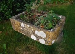A natural stone trough of rectangular form with one rounded corner,