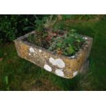 A natural stone trough of rectangular form with one rounded corner,