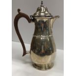 A George V silver hot water jug of pear form with ribbed belly and domed top in the Georgian style,