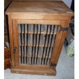 A modern pine wine cabinet, the iron railed single door enclosing four shelves for 24 bottles,