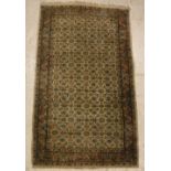 A Persian rug, the central panel set with all-over floral decoration on a cream ground,