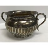 A late Victorian silver sugar basin with flared rim and wrythen embossed decoration flanked by