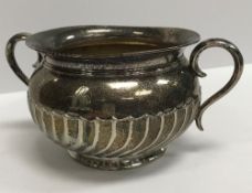 A late Victorian silver sugar basin with flared rim and wrythen embossed decoration flanked by