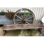A modern wooden slatted garden bench, 190 cm wide, together with a wrought iron bound wagon wheel,