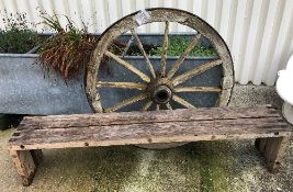 A modern wooden slatted garden bench, 190 cm wide, together with a wrought iron bound wagon wheel,