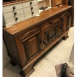 An early 20th Century oak sideboard the plain top above a single drawer by flanked by two cupboards