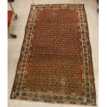 A Malayer rug, the central panel set with all-over stylised hook motifs on a red ground,