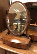 A 19th Century mahogany oval toilet mirror on a three-drawer satinwood strung bow-fronted base to