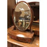 A 19th Century mahogany oval toilet mirror on a three-drawer satinwood strung bow-fronted base to