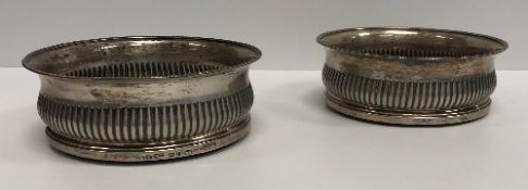 A pair of George III silver wine coasters, the flared rims with beaded edge over a reeded ogee body,