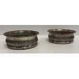 A pair of George III silver wine coasters, the flared rims with beaded edge over a reeded ogee body,