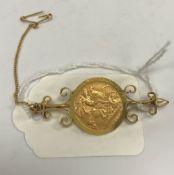 A George V gold half sovereign, 1912, in scrollwork decorated yellow metal brooch mount, 7.