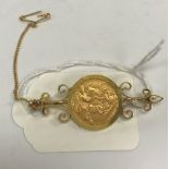 A George V gold half sovereign, 1912, in scrollwork decorated yellow metal brooch mount, 7.