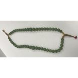 A 19th Century Chinese jade two strand bead necklace, knotted and with thread fastening,